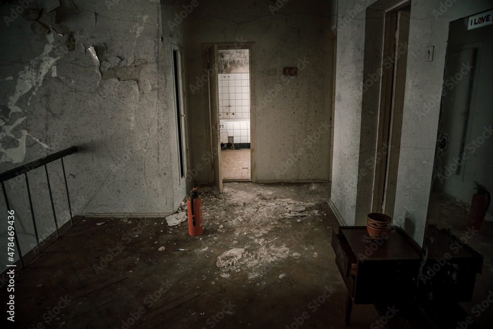 Obraz premium An old room with shabby walls in an abandoned house. Old broken doors. Dirty floor. The atmosphere of an abandoned house.