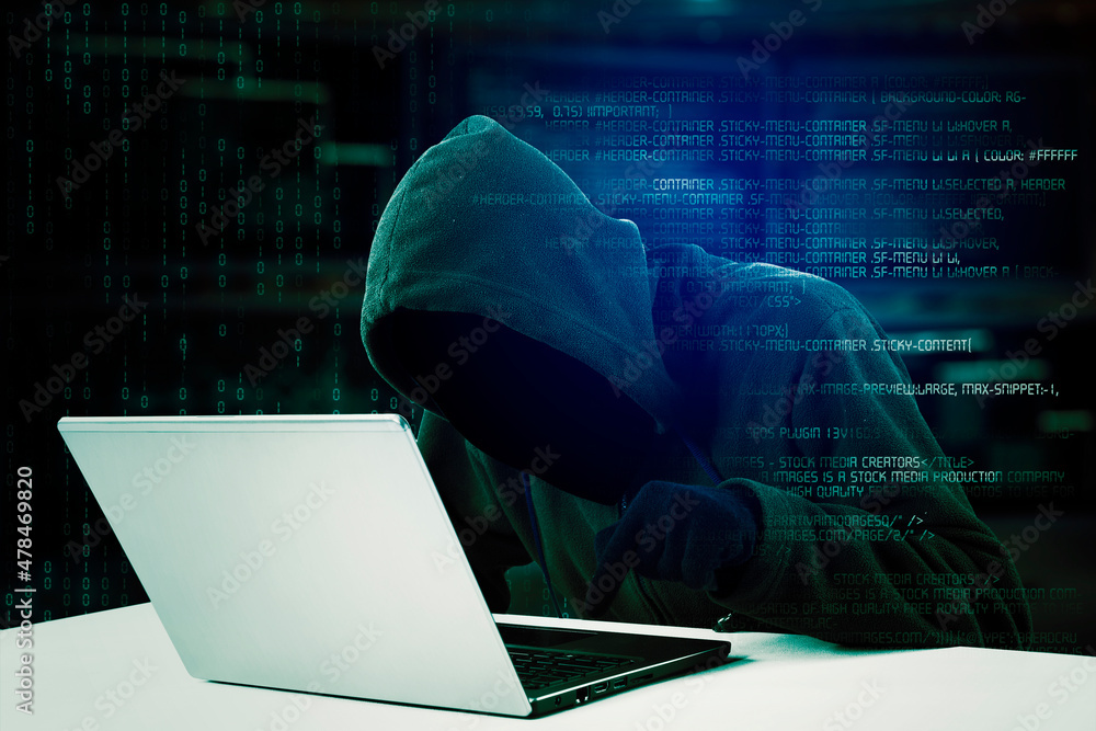 Hacker typing program code on a laptop Hacker typing program code on a laptop