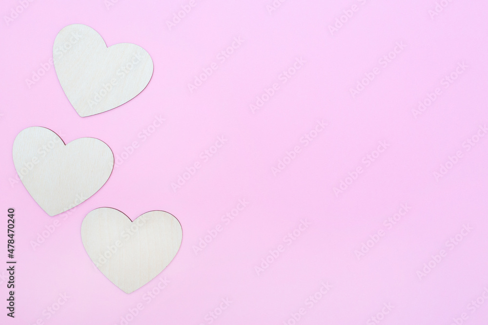 Three hearts are made of wood on a pink background. Copy space. Place for text and logo. Valentine's Day. Flat lay