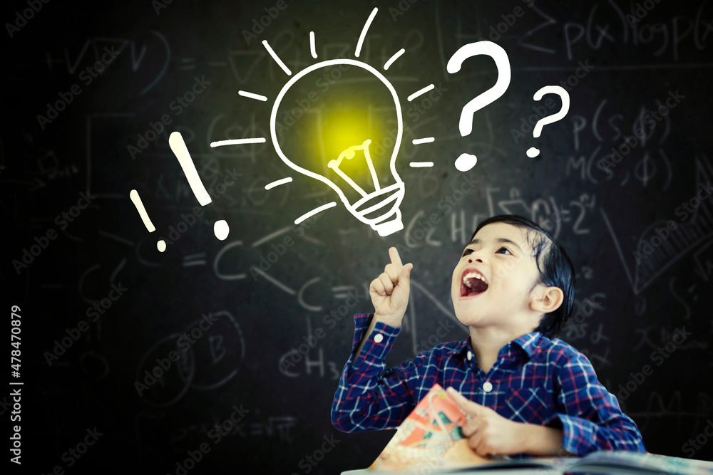 Cheerful schoolboy getting an idea in classroom