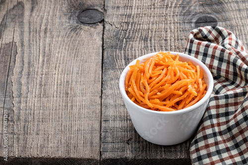 Delicious spicy carrot salad in ceramic bowl on wooden table