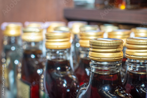 There are many small bottles of alcohol on the supermarket shelf. In the frame, the upper part of the bottles is the neck of the bottles and the cork. Selective focus