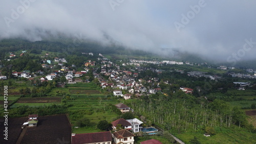 aerial photography of small city in mountains surrounded by morning fog, located in Batu, Indonesia