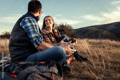 Couple sitting on grass during sunset resting after hiking.