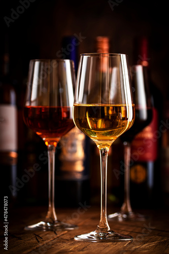 Red, white and rose wine in glasses on wooden background and collection of wine bottles, copy space © 5ph