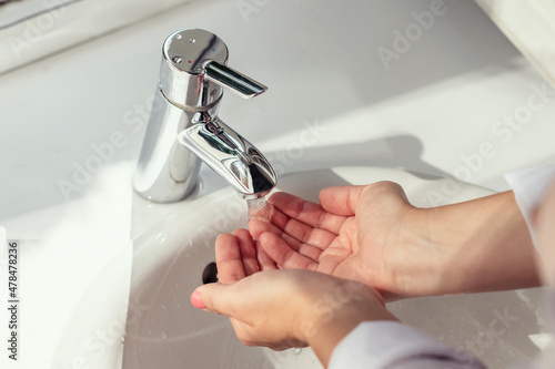 Woman washing hands under the water stream of the tap without soap. Hygiene concept. Top view