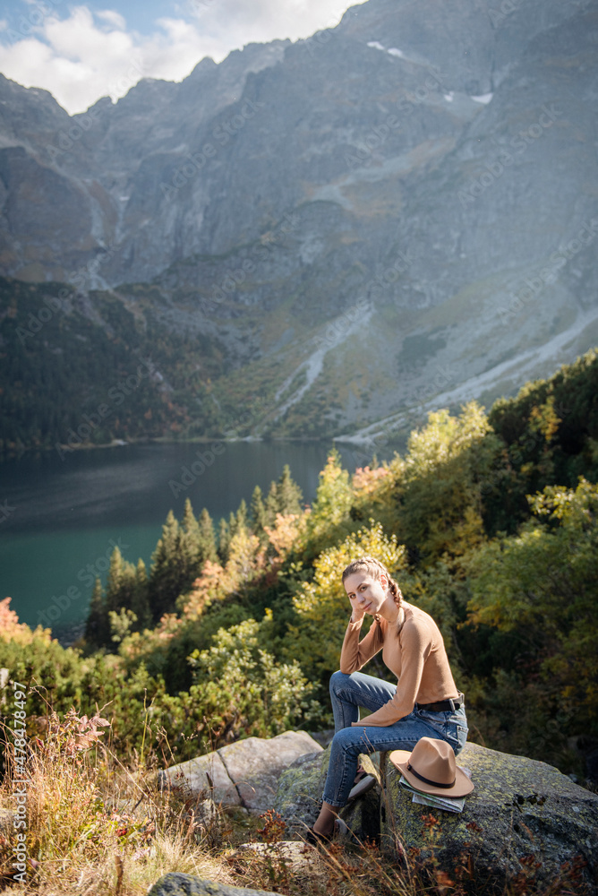 Fototapeta premium Young woman on a hiking trip sitting on a rock