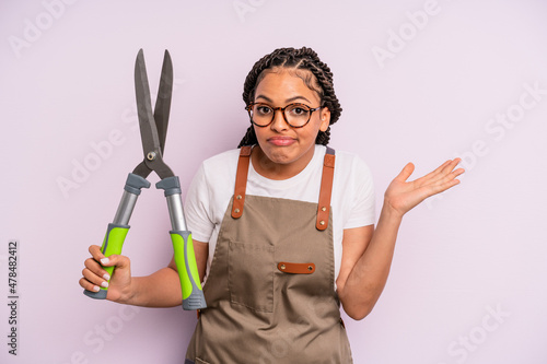 black afro woman feeling puzzled and confused and doubting. gardenner or farmer concept photo