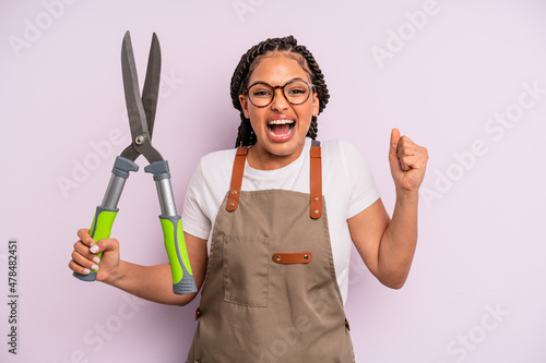 black afro woman feeling shocked,laughing and celebrating success. gardenner or farmer concept photo