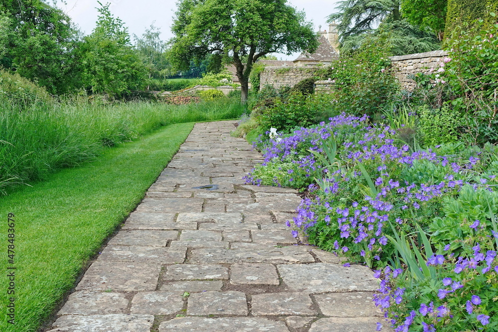 stone paved path in a beautiful garden with flowers and plants