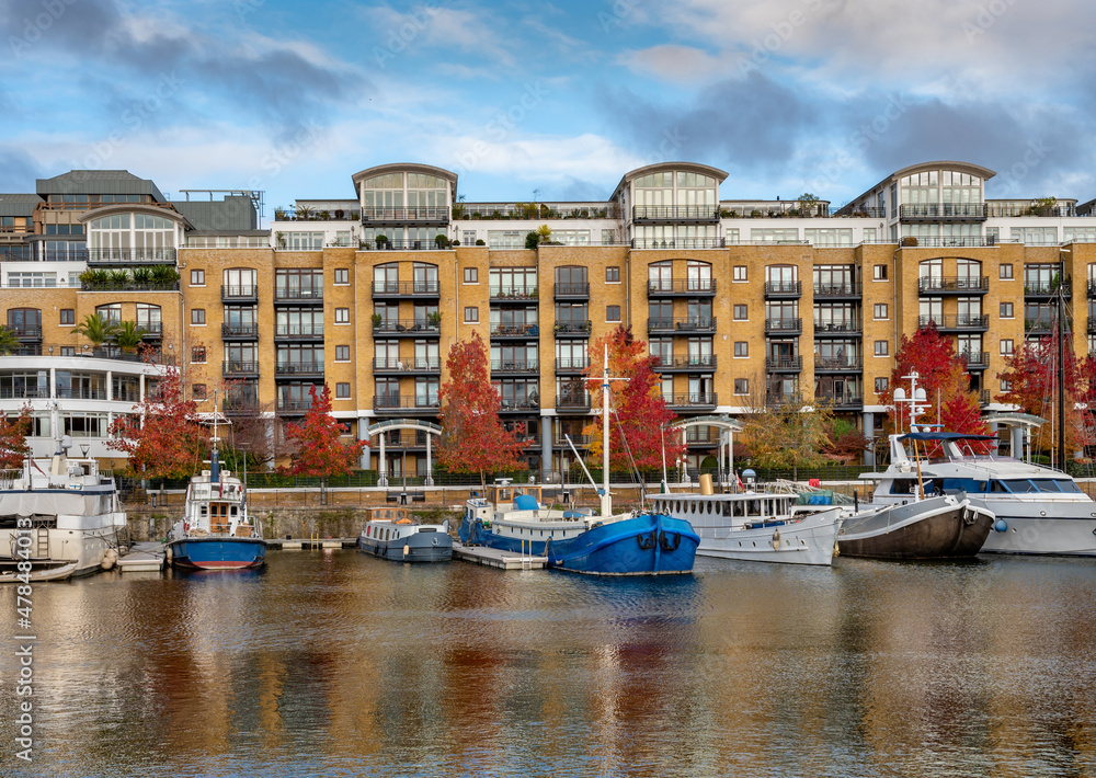 Luxury residential buildings and vintage sailing ships moored at St Katherine Dock, London.