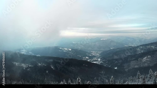 Dramatic and cinematic aerial movement - tilt up, push in. Beatifull and smooth fly above winter forest in fog into clouds.	
