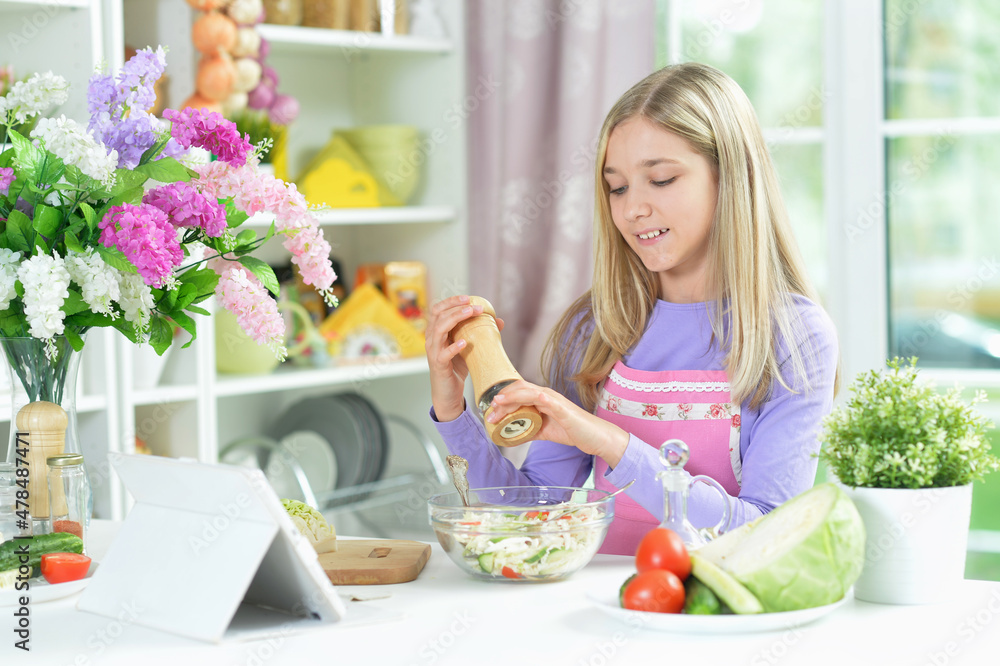 Cute girl spicing fresh salad on kitchen table Cute girl spicing fresh salad on kitchen table