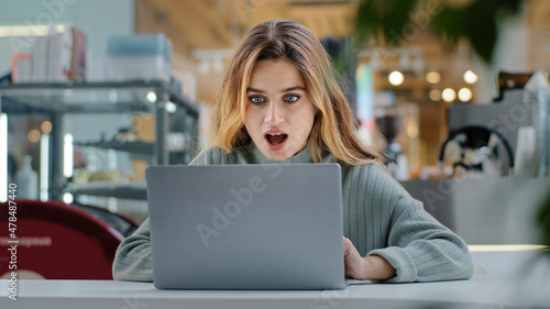 Portrait beautiful young girl student business woman female user winner looking into laptop surprised wide open mouth with delight good news applauds happiness winning opportunity new job notification