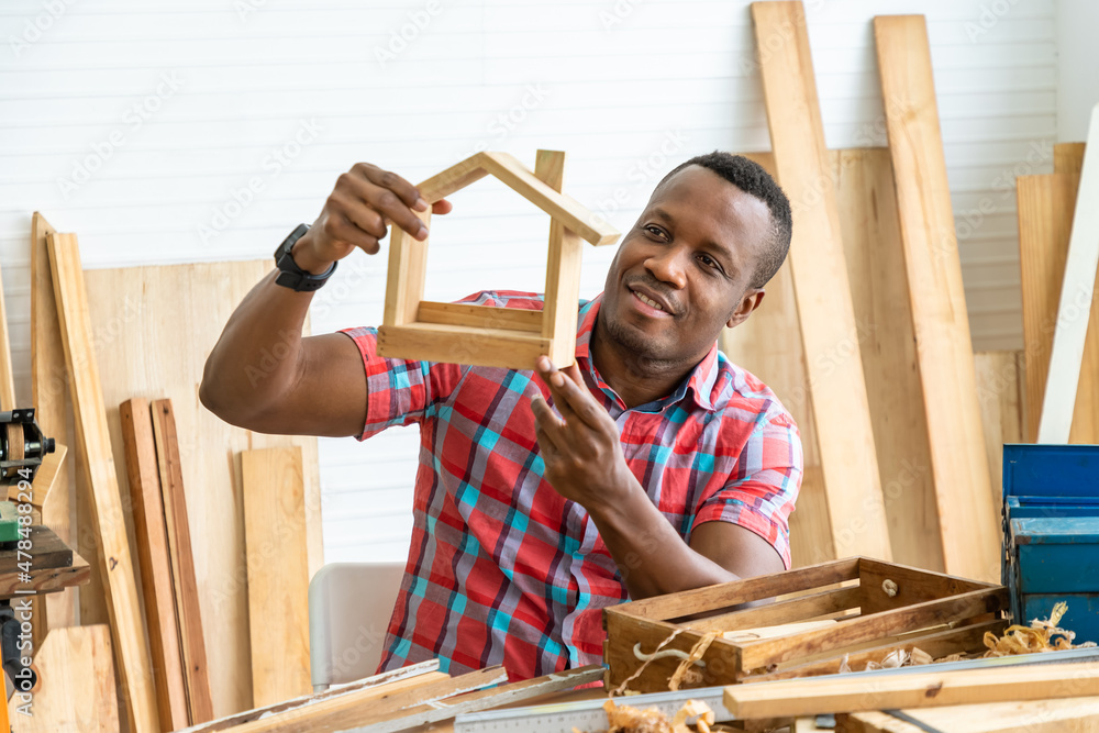 African American Male Carpenter Sitting at Table Showing Model Car