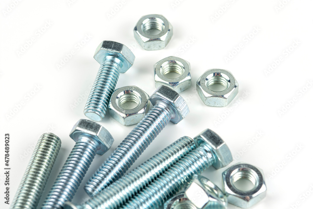 A large group of silver fasteners for fastening structures. Bolts and nuts with washers close-up on a white background. A large group of silver fasteners for fastening structures. Bolts and nuts with washers close-up on a white background.