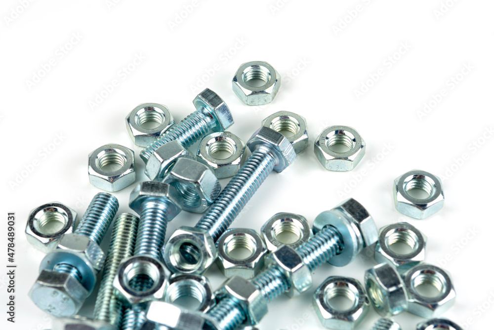 A large group of silver fasteners for fastening structures. Bolts and nuts with washers close-up on a white background. A large group of silver fasteners for fastening structures. Bolts and nuts with washers close-up on a white background.