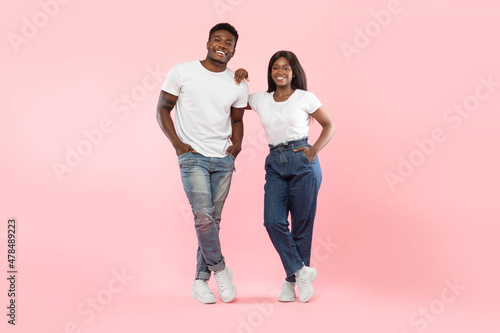 Confident couple standing posing at pink studio background