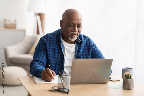 Картината върху платно Senior Black Man Using Laptop Taking Notes Working At Home