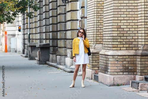 Asian woman walking in the street in a sunny summer day. Summer sunny lifestyle fashion portrait of young stylish hipster Asian woman walking on the street, wearing cute trendy outfit