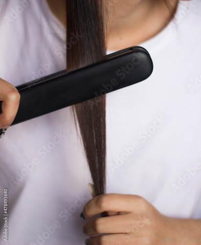 the girl straightens her hair with a curling iron