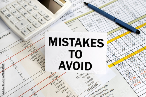 mistakes to be avoided are written on the white plate. Financial document and white calculator with a pen