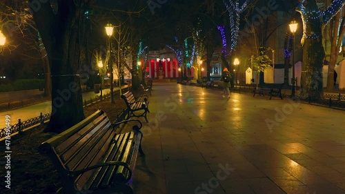 Winter evening with lonely girl  walks along the Primorsky Boulevard decorated with New Year illumination in Odessa Ukraine