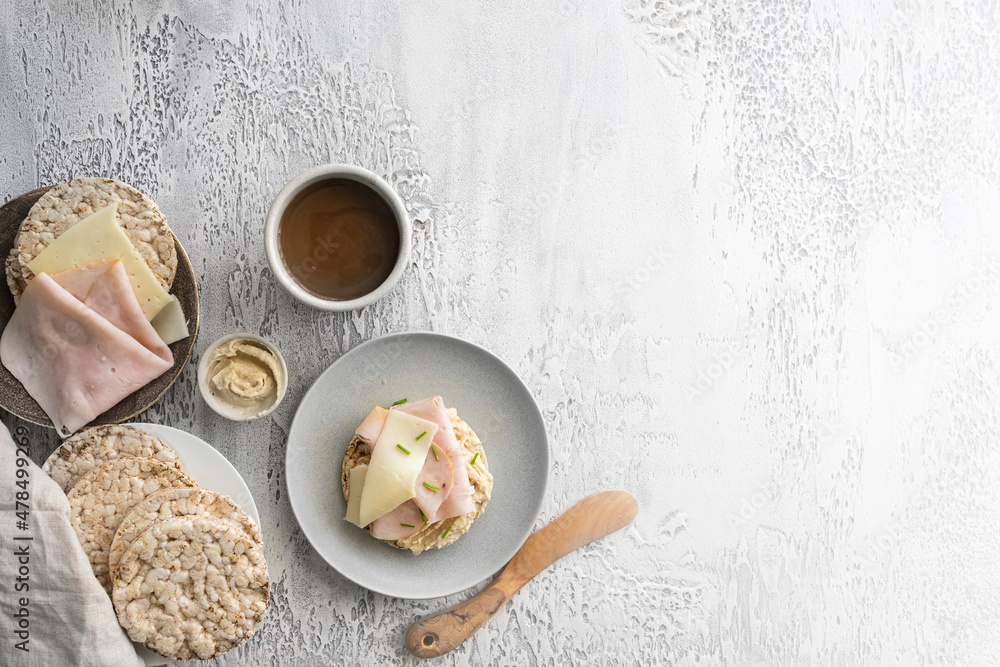 Top view of buckwheat and rice cake with hummus, ham and cheese and hot drink concrete background.Copy space. Top view of buckwheat and rice cake with hummus, ham and cheese and hot drink concrete background.Copy space.