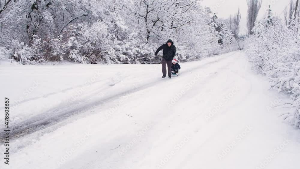 Dad sledding his son at a ski resort in a snow-covered winter forest. Dad sledding his son at a ski resort in a snow-covered winter forest.