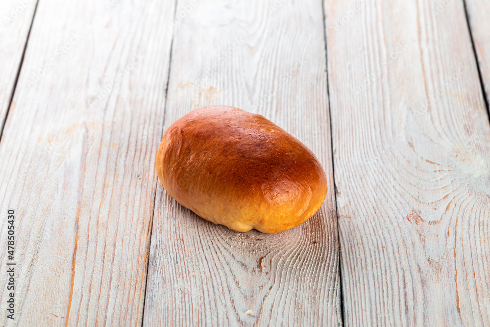 Freshly baked tasty bun on a white wooden table. Tasty baked goods straight from the bakery. White background. Freshly baked tasty bun on a white wooden table. Tasty baked goods straight from the bakery. White background.