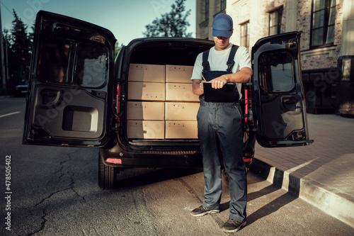 Employee in uniform logistics company.  The driver of the courier service. Fast delivery of the goods. Delivery of a box of products and goods to your home. © muse studio