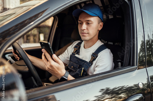 The driver of the courier service uses the phone to deliver groceries and goods to the house. A uniformed employee. photo