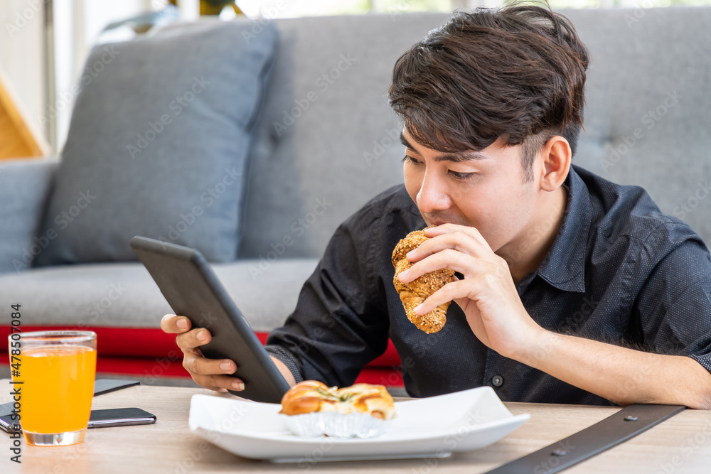 Asian businessman freelance sitting on floor front of sofa using table with meal breakfast. Concept for working at home. Asian businessman freelance sitting on floor front of sofa using table with meal breakfast. Concept for working at home.