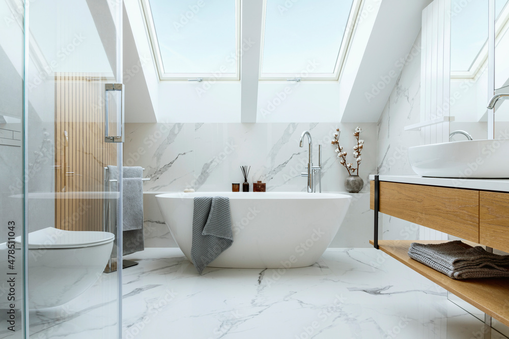 Stylish bathroom interior design with marble panels. Bathtub, towels and other personal bathroom accessories. Modern glamour interior concept. Roof window. Template.. - obrazy, fototapety, plakaty 