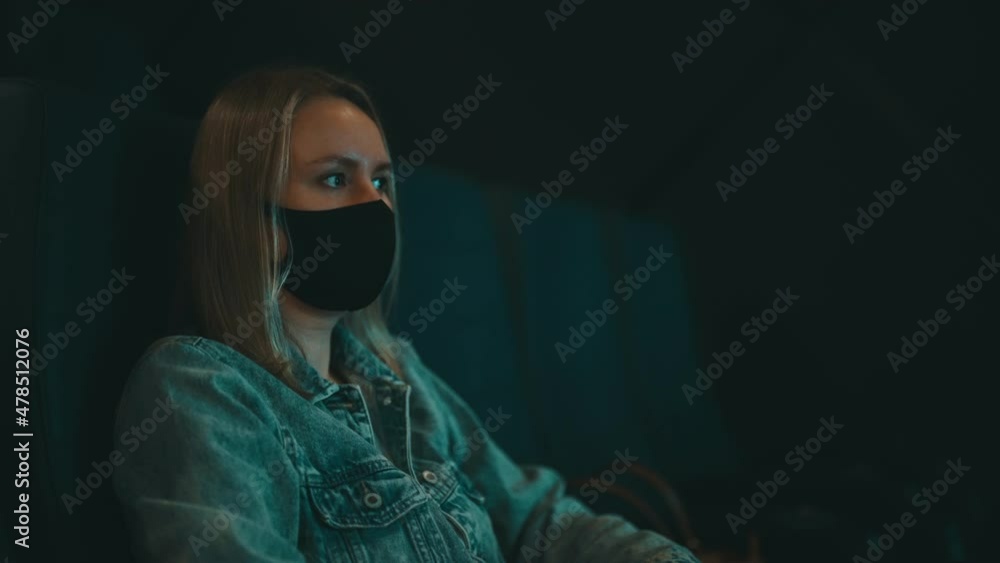 Woman in medical mask is watching movie in the cinema. Woman in medical mask is watching movie in the cinema.