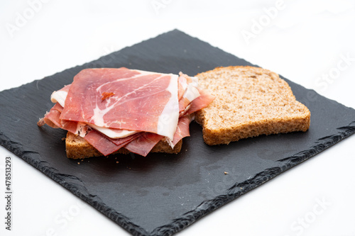 wholemeal bread sandwich with raw ham and salad on a white background