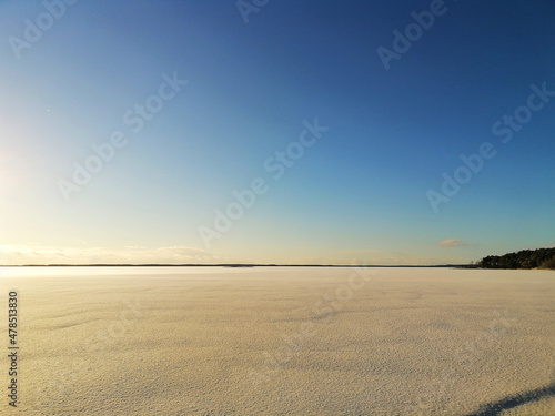 Rekyva lake during sunny winter day. Snow is covering frozen lake ice. Clear blue sky. Horizon. Winter season. Minimalistic photo.