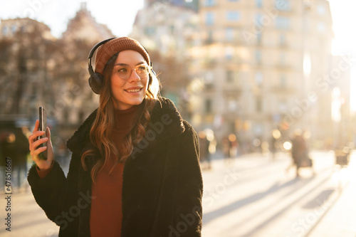 Pretty girl listening music with her headphones. Beautiful woman enjoy in sunny day.