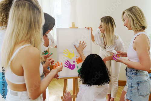 Group of women paint on canvas and drinking white wine during party at home
