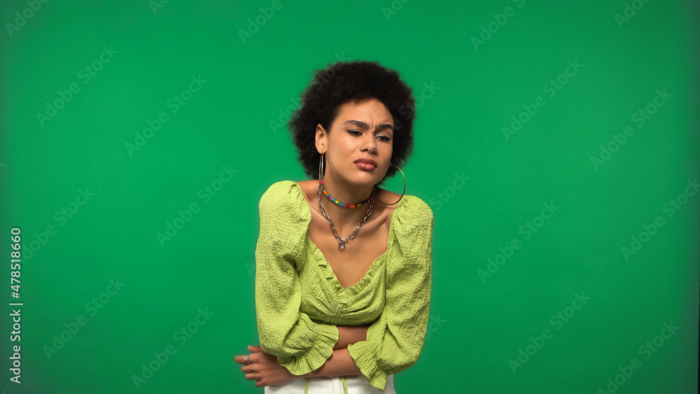 Obraz premium young african american woman in hoop earrings having stomach ache isolated on green