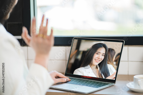 Happy young Asian female manager has an online interaction with partners and clients showing on the laptop screen