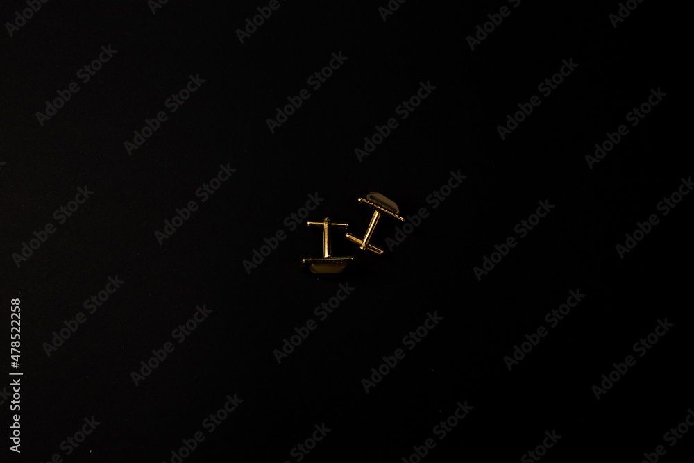 Gold men's cufflinks with stones lie on a black background