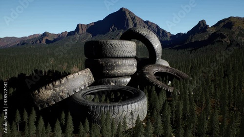 concept of environmental pollution with big old tires in mountain forest photo