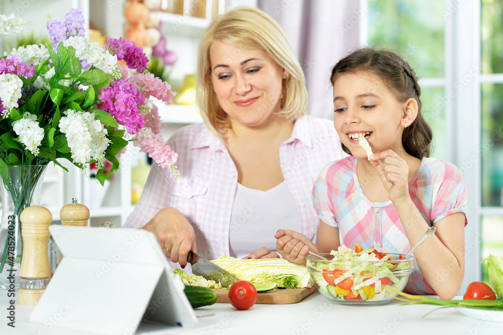 Cute little girl with her mother cooking together Cute little girl with her mother cooking together