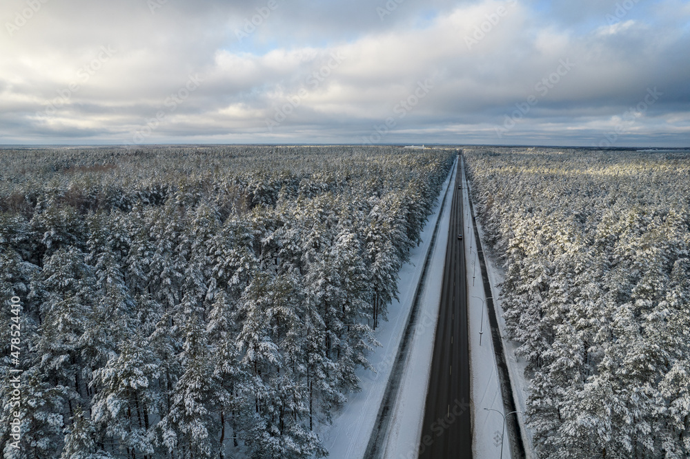 Aerial view of asphalt highway leading through frosty winter forests and groves covered with hoarfrost and snow. Drone photo of black road line and trees with chill snow in mountains. Christmas theme Aerial view of asphalt highway leading through frosty winter forests and groves covered with hoarfrost and snow. Drone photo of black road line and trees with chill snow in mountains. Christmas theme