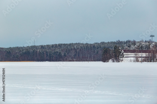 Winter landscape. Frozen lake in the snow. Forest in the background. © Людмила Щетинина