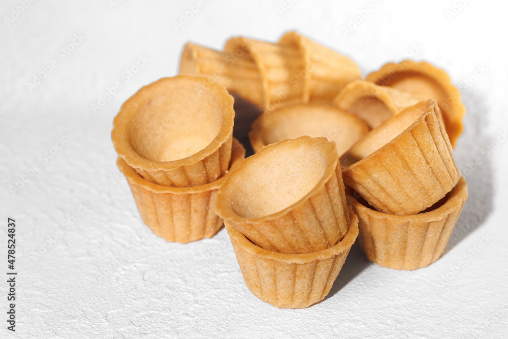 Homemade empty tartlets baskets of puff pastry, isolated on a white background.