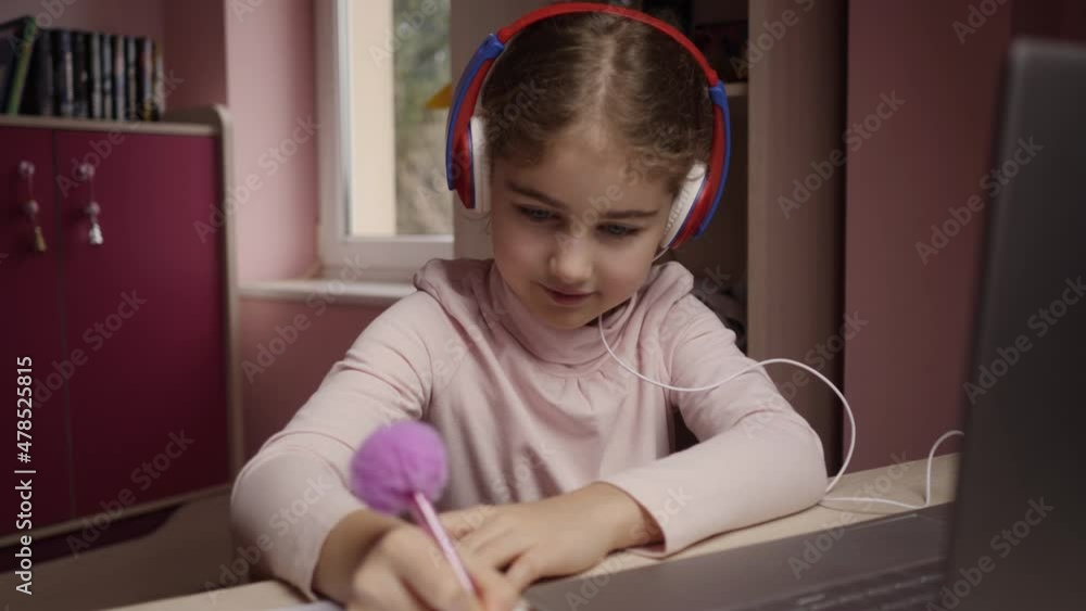 Distance Learning. Schoolgirl Studying Online Using Laptop Making Notes in Copybook. School Student Wearing Headphones Watching Internet Video Course. Caucasian Girl Wear Headphones Learn Online Class Distance Learning. Schoolgirl Studying Online Using Laptop Making Notes in Copybook. School Student Wearing Headphones Watching Internet Video Course. Caucasian Girl Wear Headphones Learn Online Class