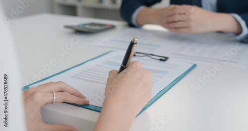 Close-up hand asia people woman fill rent loan form write legal debt letter at lawyer home office. Happy female life buy or sell new house deal from real estate sale agent. Tax advice talk and smile.