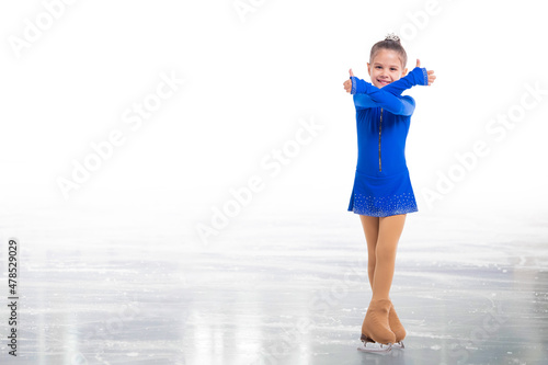 A Little young skater posing in blue training dress on ice showing success gesture isolated on white background © Maria Moroz